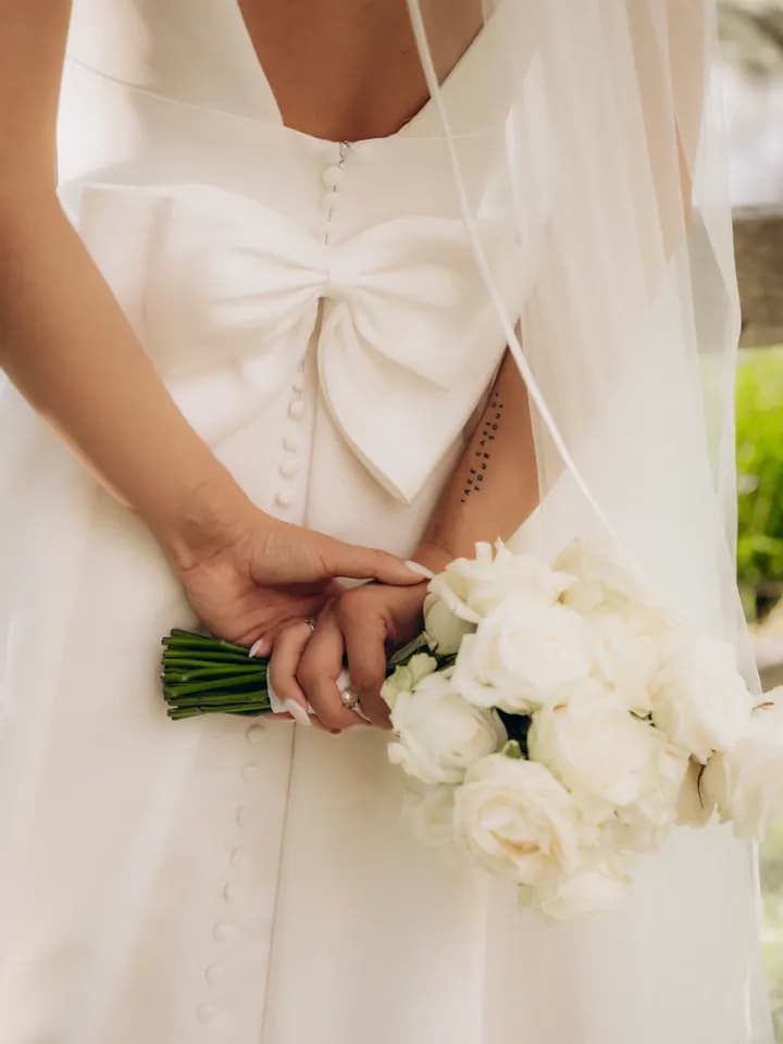 Schleife des Brautkleids und weißer Strauß im Detail