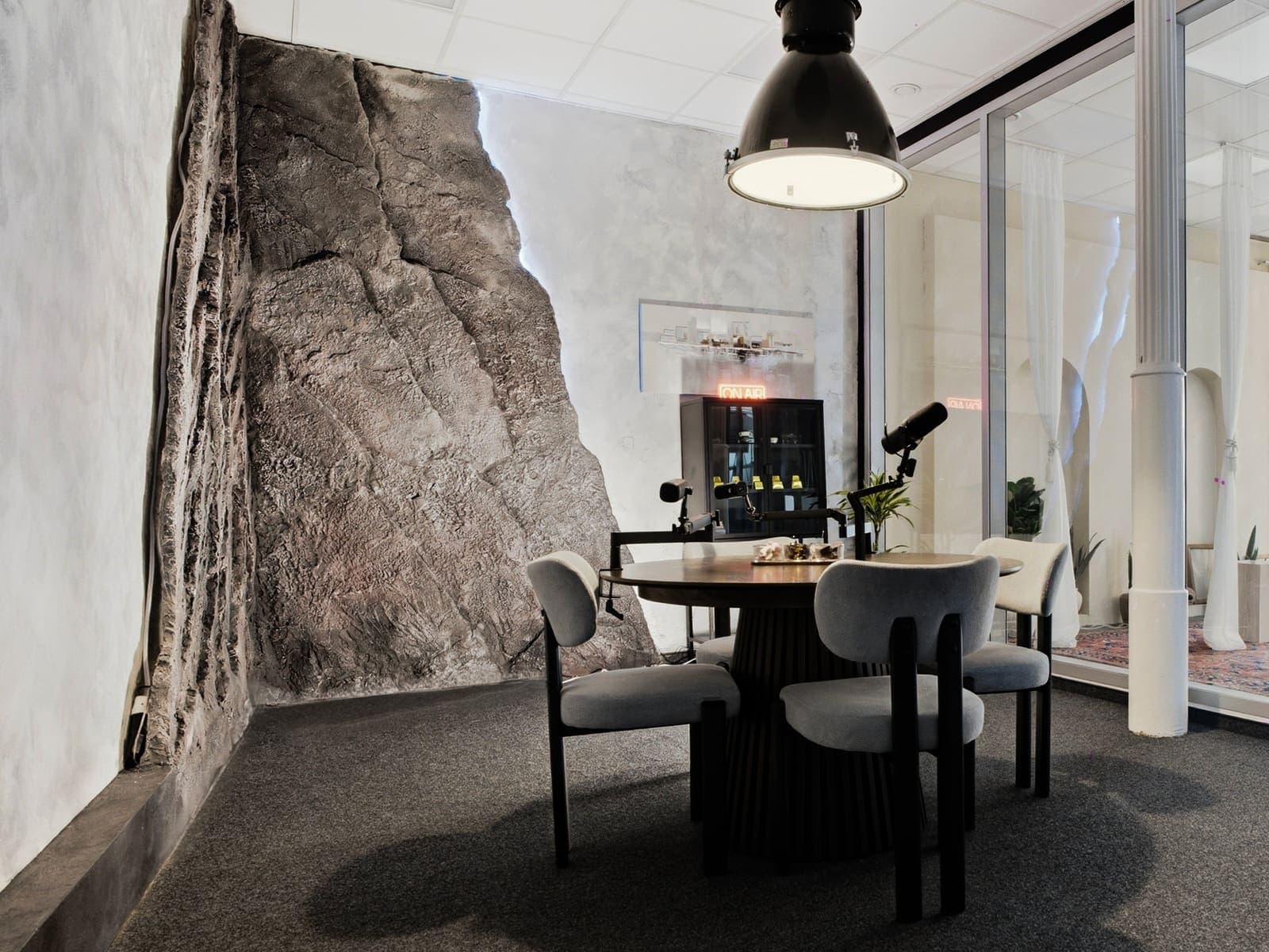 Tisch mit Podcast-Mikrofonen vor der Steinwand im warmen Licht der Industrie-Lampe