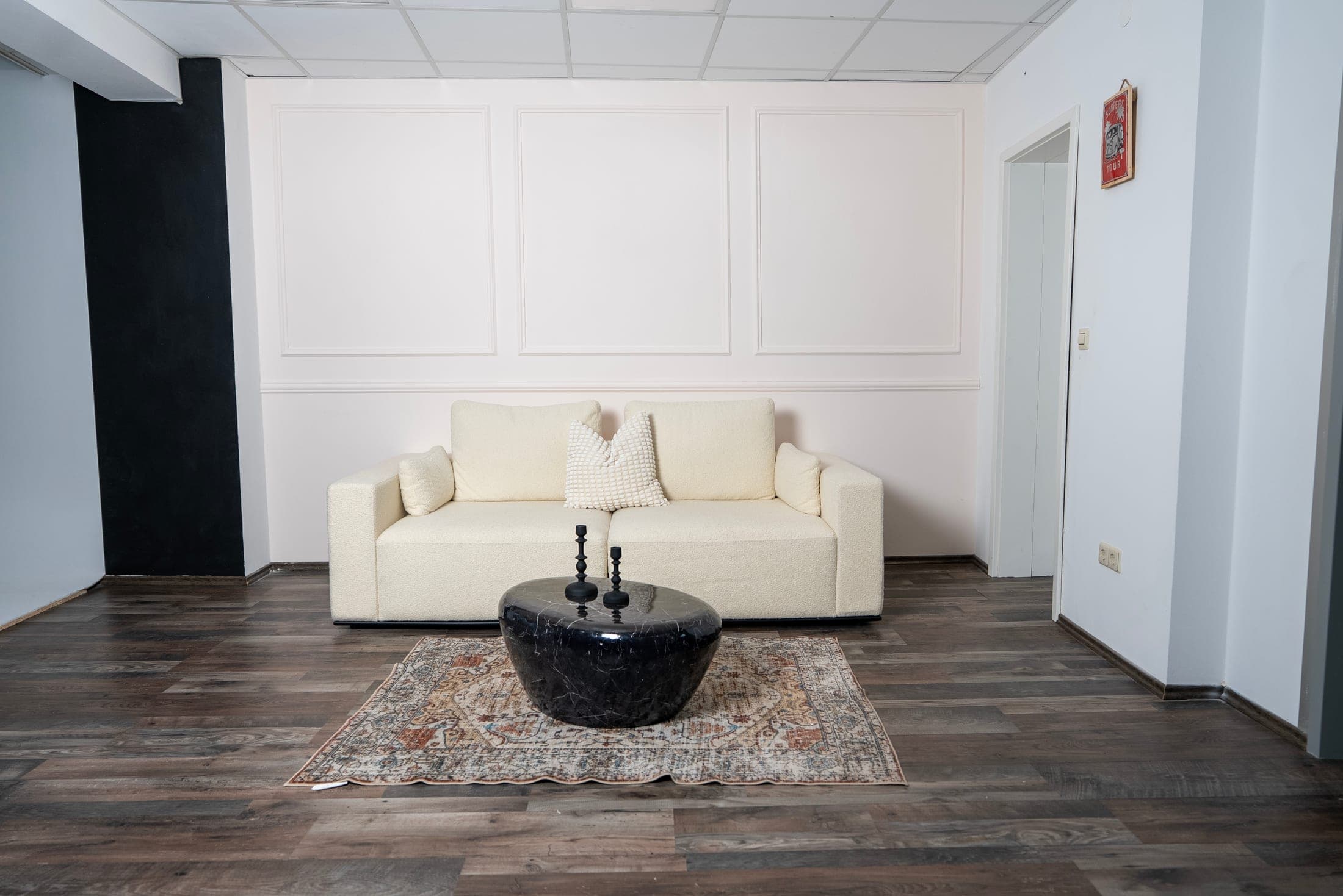 Wohnzimmer-Kulisse mit weißer Stuckwand und cremefarbenem Bouclé-Sofa