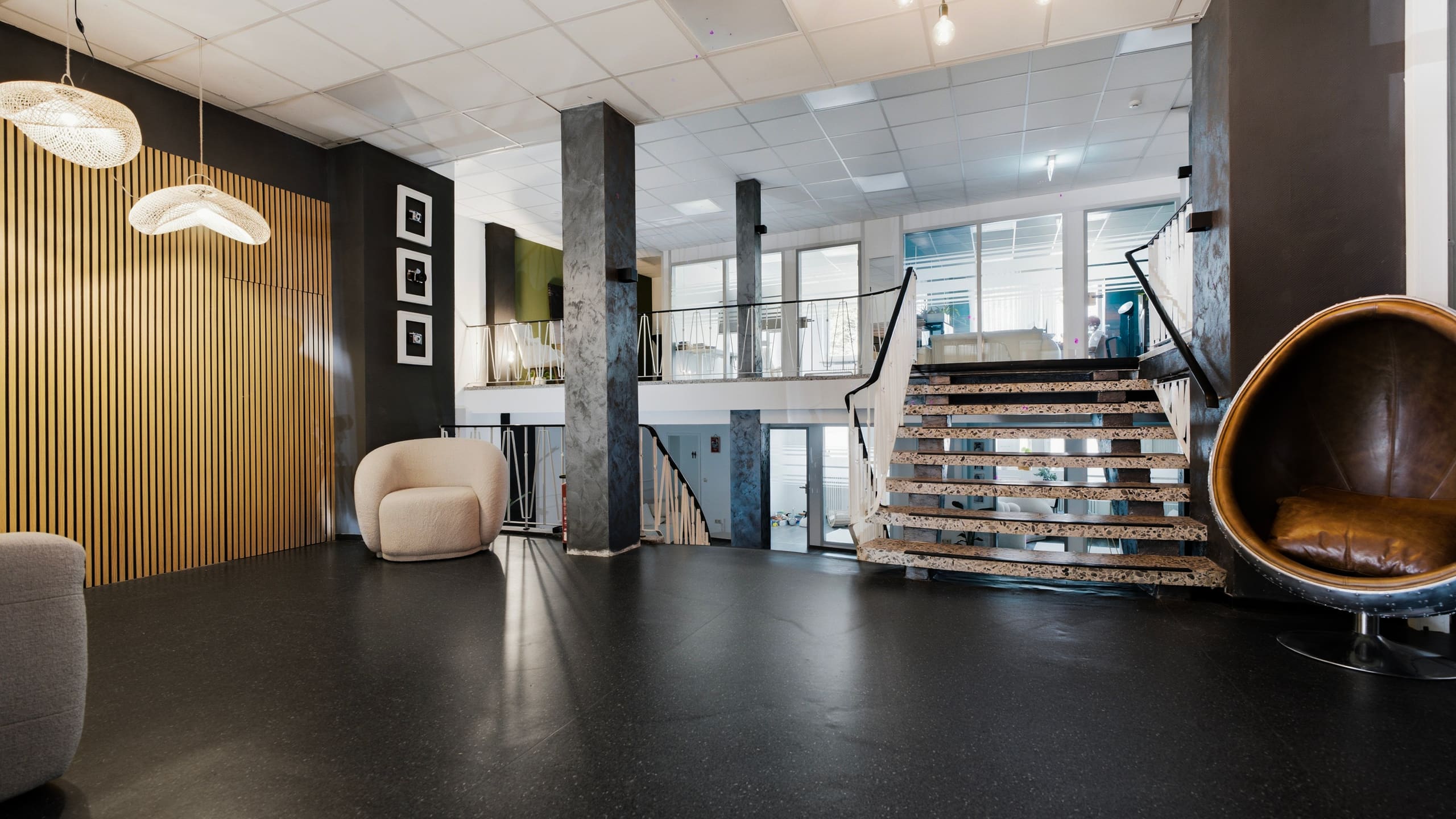 Studiohalle mit offener Treppe, Holz-Latten-Wand und Egg-Chair